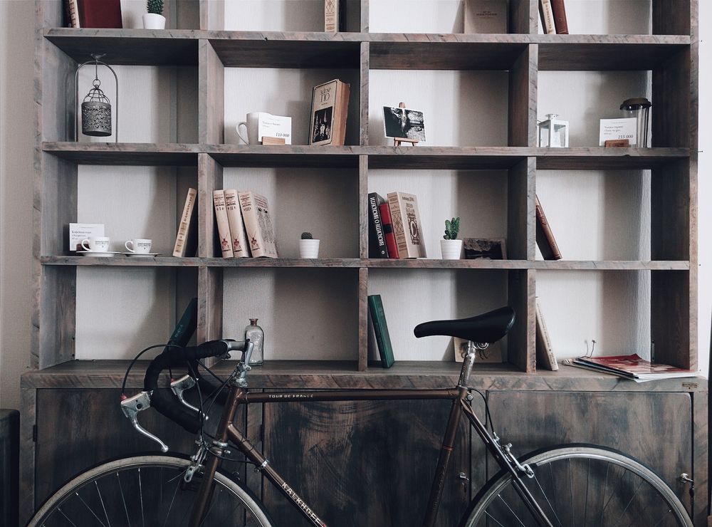 En cykel inomhus framför en bokhylla.